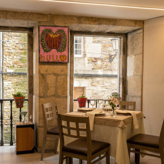 Mesa para dos en restaurante con ventanas de piedra y decoración floral