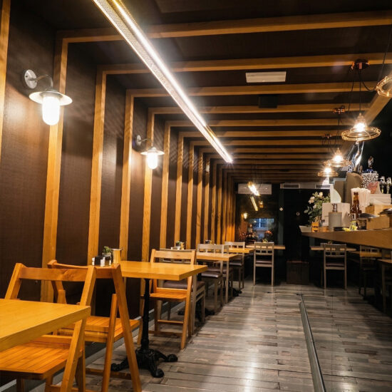 Restaurante con diseño moderno, sillas de madera y luces colgantes.